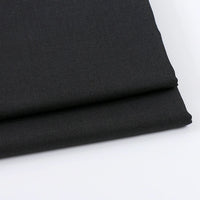 A close-up of two neatly folded pieces of Longan Craft Solid Color Wool Gabardine Fabric, a rayon polyester blended twill ideal for casual wear, displayed on a white surface.