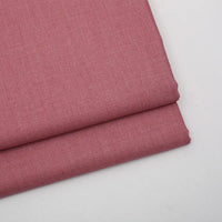 Two pieces of Longan Craft Solid Color Wool Gabardine Fabric, a smooth rayon-polyester twill ideal for casual wear, are stacked on a white surface, showcasing its fine weave and soft dusty pink color.