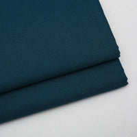 Two neatly folded pieces of Longan Craft Solid Color Wool Gabardine Fabric rest on a light surface, showcasing the smooth, slightly textured rayon-polyester blended twill—ideal for casual wear.