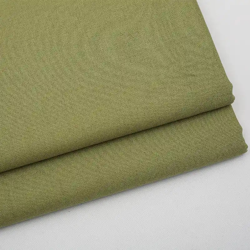 Two neatly folded pieces of Longan Craft's Solid Color Wool Gabardine Fabric By The Yard, a rayon-polyester blended twill ideal for casual wear, are stacked on a white surface, highlighting the fabric’s smooth and slightly textured weave.