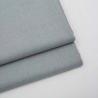 Two pieces of Longan Craft Solid Color Wool Gabardine Fabric are neatly folded on a white surface, displaying a smooth, soft texture. This rayon polyester blended twill is ideal for casual wear and sold by the yard.