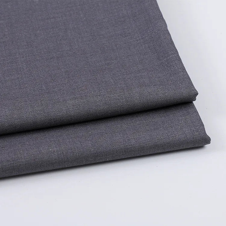Two neatly folded pieces of Longan Craft Solid Color Wool Gabardine Fabric By The Yard, a rayon polyester blended twill ideal for casual wear, are stacked on a white surface, displaying a subtle weave texture in dark gray.