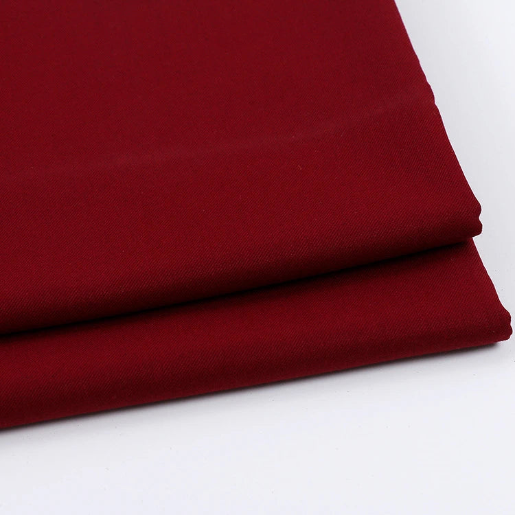 Two neatly folded pieces of Longan Craft Solid Color Wool Gabardine Fabric by the yard, a rayon polyester blended twill gabardine material, are placed on a white surface—ideal for casual wear.