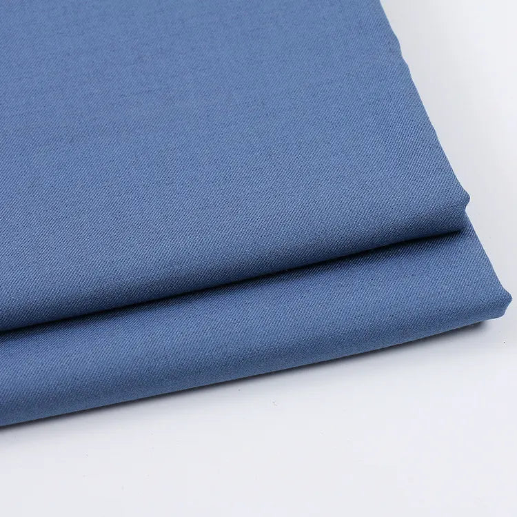 A neatly folded piece of Longan Craft Solid Color Wool Gabardine, a rayon-polyester blended twill fabric ideal for casual wear, lies on a white surface, highlighting its smooth texture and clean edges.