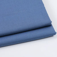 A neatly folded piece of Longan Craft Solid Color Wool Gabardine, a rayon-polyester blended twill fabric ideal for casual wear, lies on a white surface, highlighting its smooth texture and clean edges.