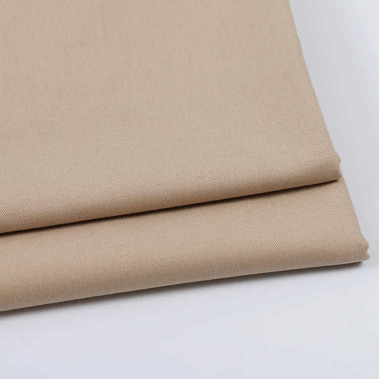 Two neatly folded pieces of Longan Craft Solid Color Wool Gabardine Fabric are stacked on a white surface, highlighting the smooth, even texture of this rayon polyester blended twill—ideal for casual wear.