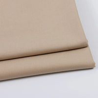 Two neatly folded pieces of Longan Craft Solid Color Wool Gabardine Fabric are stacked on a white surface, highlighting the smooth, even texture of this rayon polyester blended twill—ideal for casual wear.