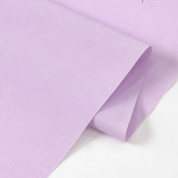 A close-up of two overlapping sheets of Longan Craft's Solid Cotton Lawn Fabric by the yard, highlighting the smooth texture and soft pastel tone of this cozy polyester lawn cloth material.