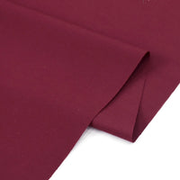 A close-up of Longan Craft's Solid Cotton Lawn Fabric by the Yard, a maroon polyester-cotton blend lawn cloth material, shown smoothly folded on a flat surface.