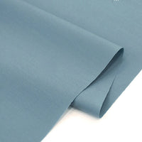 A close-up of Longan Craft’s Solid Cotton Lawn Fabric by the Yard, a smooth, light blue polyester lawn cloth material, shown slightly folded to display its cozy texture and thickness against a white background.