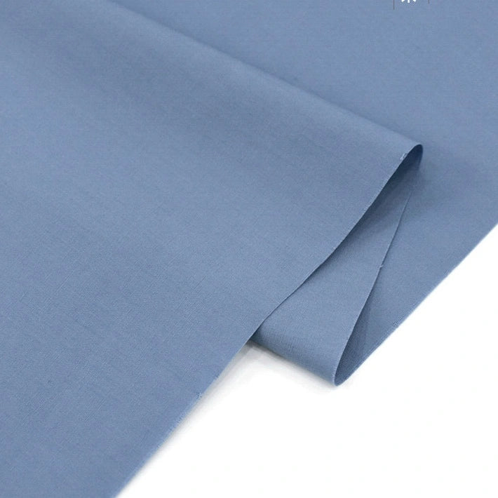 A close-up of Longan Craft's Solid Cotton Lawn Fabric by the yard, neatly folded on a white surface, highlights its smooth, soft, and breathable polyester lawn cloth material—perfect for cozy lawn dress projects.