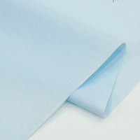 A close-up of Longan Craft’s Solid Cotton Lawn Fabric By The Yard, a light blue polyester lawn cloth material, partially folded on a white surface. Ideal for cozy lawn dress fabric projects.