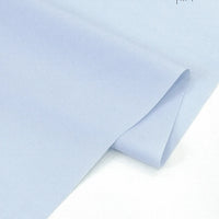 A close-up of Longan Craft's Solid Cotton Lawn Fabric by the yard, a soft blue cotton-polyester cloth for cozy dresses, with a slightly curled edge on a white background.