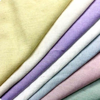 Several pieces of Longan Craft Solid Color Viscose Lyocell Fabric, in pastel yellow, cream, lavender, light blue, and pink, are neatly layered for a soft and sustainable look. This smooth rayon lyocell textile is perfect for tops.