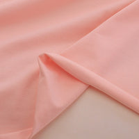 A close-up of Longan Craft's Spandex Jersey Fabric By The Yard highlights its soft, light pink cotton jersey, smooth texture, gentle drape, and impressive four-way stretch—ideal for dresses and more.