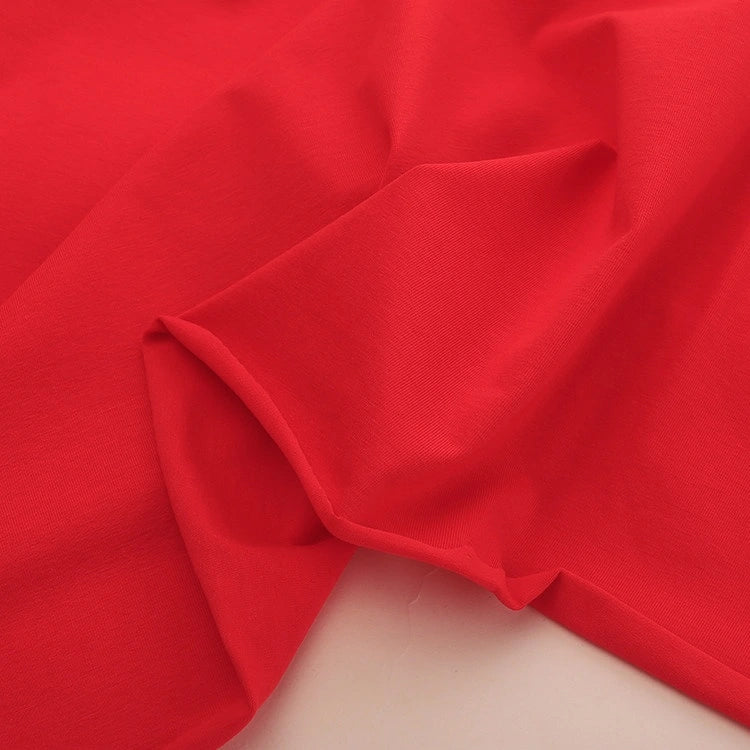 A close-up of Longan Craft’s Spandex Jersey Fabric By The Yard in vibrant red, showing its smooth, slightly wrinkled cotton jersey texture and four-way stretch—ideal for dresses and projects needing solid color stretch fabric.