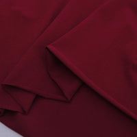 A close-up of folded maroon Spandex Jersey Fabric By The Yard from Longan Craft, showing its smooth, soft texture and clean edges against a plain background. Ideal as a solid color cotton stretch jersey dress fabric.