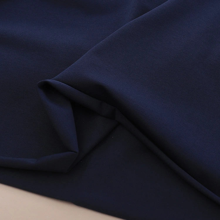 A close-up of smooth, dark navy blue Spandex Jersey Fabric from Longan Craft, featuring gentle folds and a soft texture. Available by the yard as Solid Color Cotton Jersey Stretch Dress Fabric.