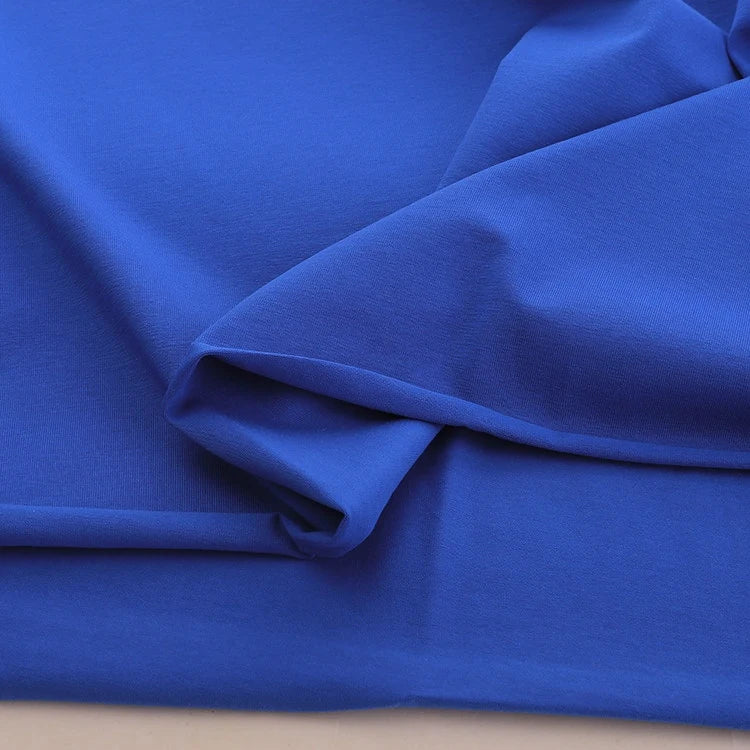 A close-up of Longan Craft Spandex Jersey Fabric By The Yard in royal blue, showing its vibrant color, soft folds, and four-way stretch—ideal as a solid color cotton jersey fabric for comfortable dressmaking projects.