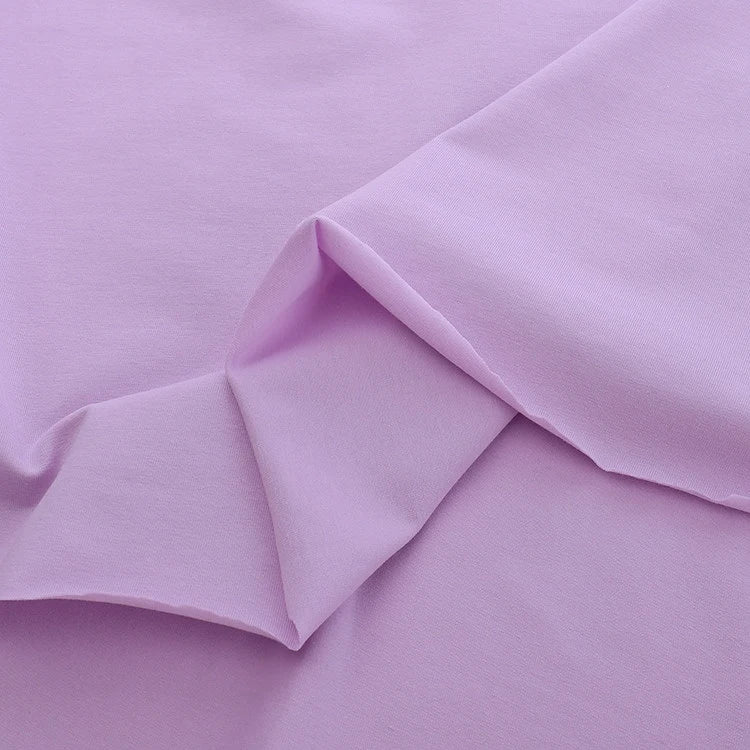 A close-up of Longan Craft’s Spandex Jersey Fabric By The Yard in light purple, featuring a smooth, stretchy cotton jersey texture with soft folds and slightly overlapping edges.