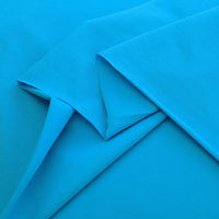 Multiple pieces of Longan Craft's Spandex Jersey Fabric By The Yard in bright blue are neatly layered, highlighting its smooth texture, clean edges, lightweight feel, and impressive four-way stretch—ideal for dressmaking.