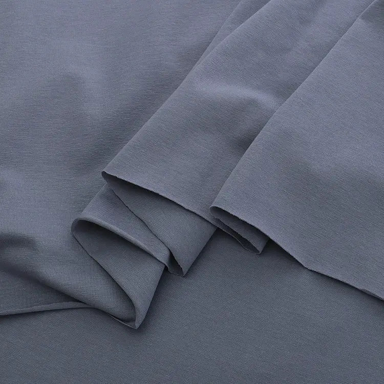 Overlapping pieces of Longan Craft's Spandex Jersey Fabric By The Yard in dark grey display its soft texture, clean edges, and subtle four-way stretch—ideal as a solid color cotton jersey stretch dress fabric.