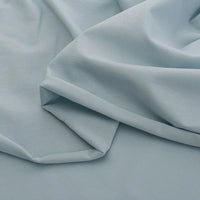 A close-up of Longan Craft’s Spandex Jersey Fabric By The Yard in light blue, featuring soft folds, smooth texture, and four-way stretch that creates gentle shadows and highlights. Perfect solid color cotton jersey fabric for dresses.
