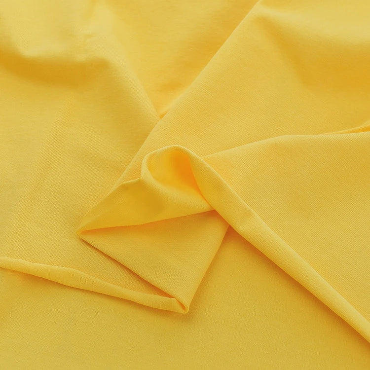 A close-up of Longan Craft’s Spandex Jersey Fabric By The Yard highlights its soft texture, vibrant yellow color, and impressive four-way stretch, ideal for dresses and crafts.