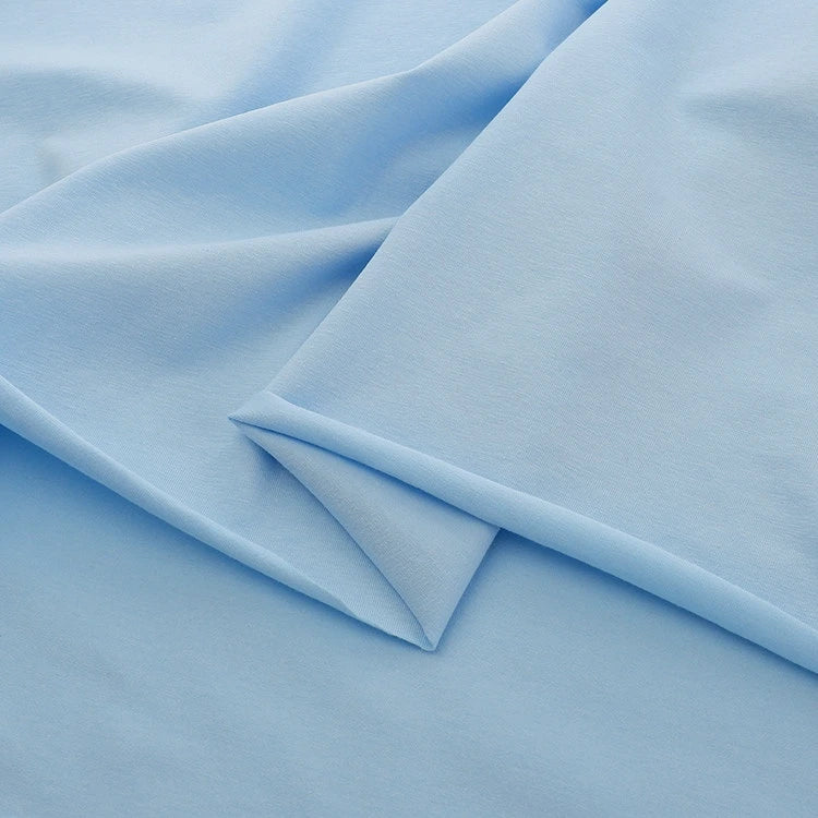 A close-up of Longan Craft’s Spandex Jersey Fabric By The Yard in light blue, laid flat to highlight its smooth, even texture and soft four-way stretch—ideal as a solid color cotton jersey dress fabric.