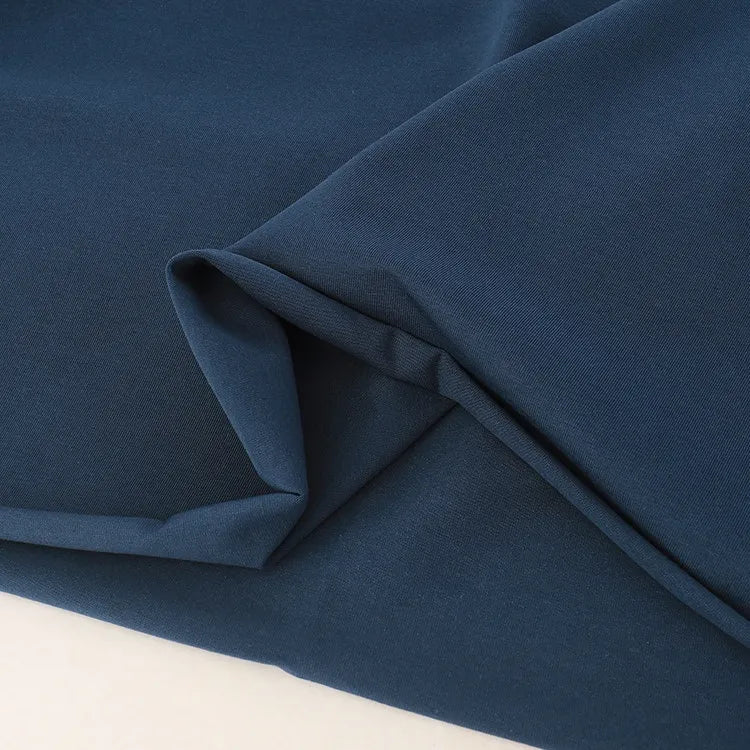 A close-up of Longan Craft Spandex Jersey Fabric By The Yard in dark blue, neatly folded to show its soft, smooth texture and slight sheen, set against a light background.