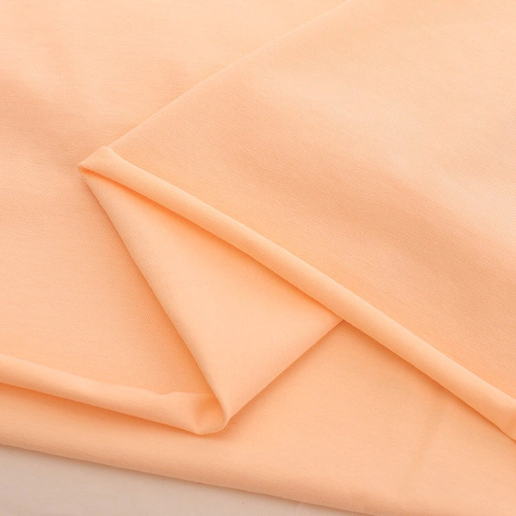 A close-up of peach Spandex Jersey Fabric by the yard from Longan Craft, made of a cotton-spandex blend with a smooth, soft texture and clean lines—ideal as solid color stretch jersey dress fabric.