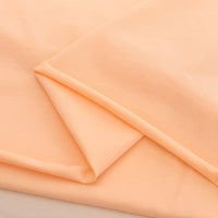 A close-up of peach Spandex Jersey Fabric by the yard from Longan Craft, made of a cotton-spandex blend with a smooth, soft texture and clean lines—ideal as solid color stretch jersey dress fabric.