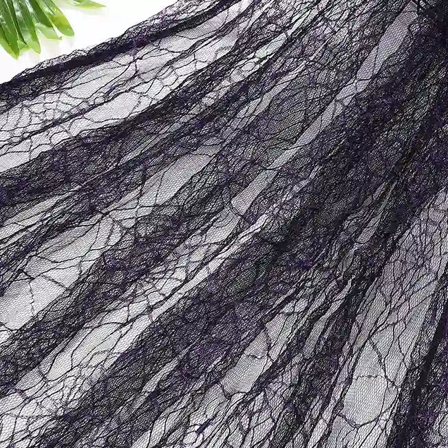 A close-up of Longan Craft’s Spider Web Tulle Fabric by the yard shows its intricate web pattern—ideal colorful Halloween tulle for DIY party dresses. Green leaves appear in the top left corner.