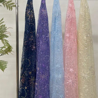 Five sheer Star and Moon Sequin Embroidered Tulle Fabrics by Longan Craft in navy, purple, light blue, pink, and ivory hang beside green ferns. Each features glittery stars, moons, and fireworks—perfect for DIY wedding dresses.