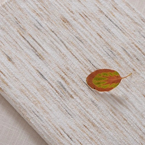 A single brown and green leaf rests on Striped Jacquard Chenille Fabric by Longan Craft, a durable, colorful poly woven chenille upholstery material.