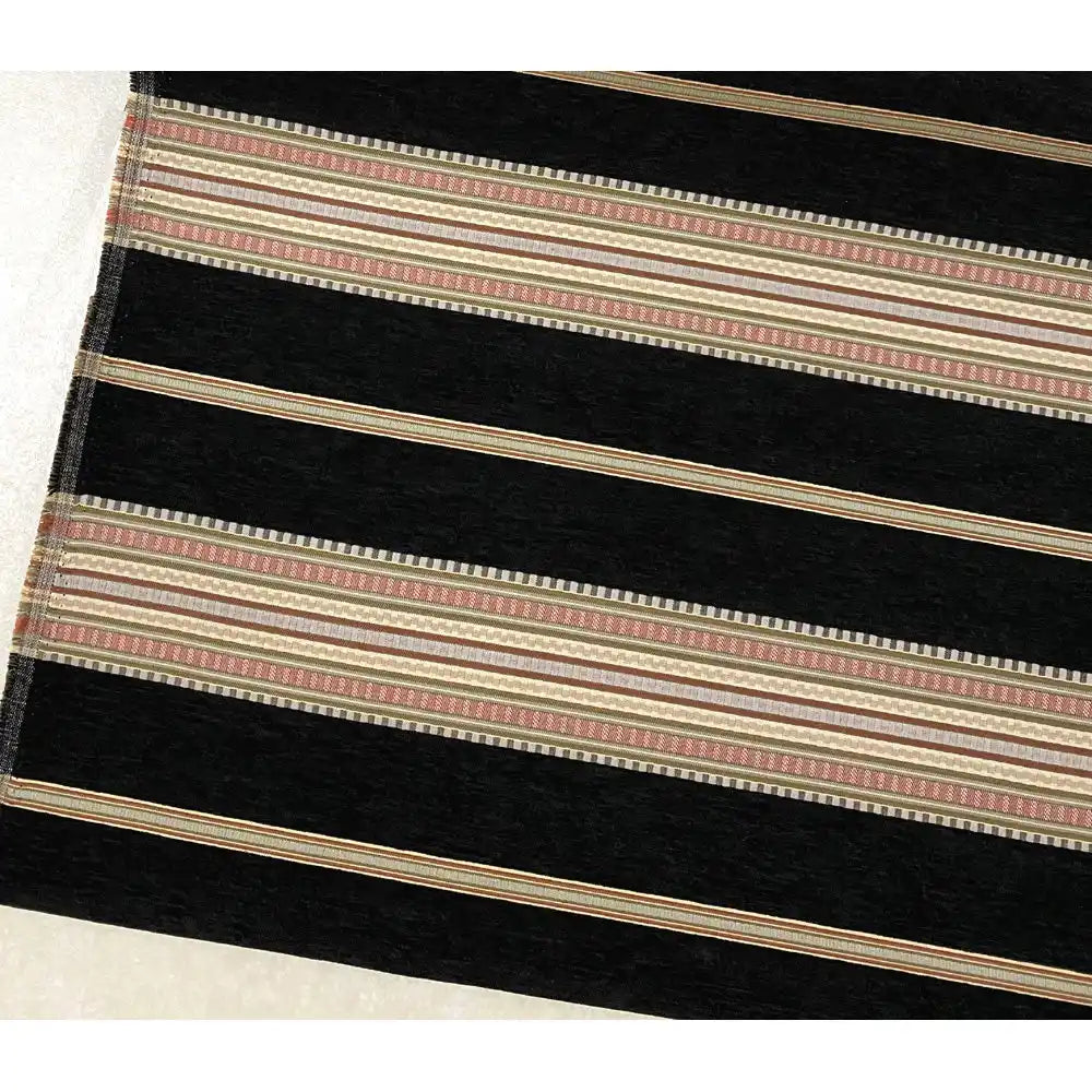 A section of the Longan Craft Striped Jacquard Chenille Fabric By The Yard, featuring wide black and narrow beige stripes with red and tan patterns, is laid on a light floor. This 100% poly chenille upholstery fabric is high-quality and perfect for cushions.