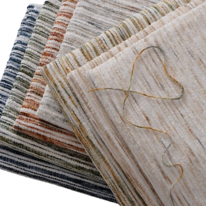 Stack of folded, textured Striped Jacquard Chenille Fabric By The Yard from Longan Craft, featuring colorful horizontal stripes. A loose thread forms a heart on top—ideal for upholstery projects with this durable poly woven chenille material.