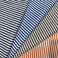 Four pieces of Longan Craft's Striped Print Lawn Fabric By The Yard—pure cotton in black, blue, brown, and orange stripes—are laid diagonally side by side, highlighting the fabric’s classic striped design and soft texture for shirts.