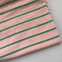 A piece of Longan Craft Striped Printed Gauze Fabric By The Yard, made from double 100% cotton with a pink background and evenly spaced horizontal green and white stripes, shown on a light gray surface.