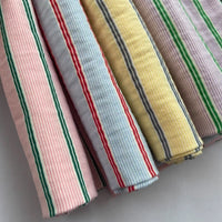 Four pieces of Longan Craft Striped Printed Gauze Fabric By The Yard in cotton: pink/green/white, blue/red/white, yellow/gray/white, and lavender/green/white stripes. Breathable double gauze; cozy material.