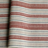 A close-up of Longan Craft’s Striped Printed Linen Fabric By The Yard, a cotton linen blend featuring colorful horizontal stripes in red, white, and blue with small geometric patterns. The breathable fabric is slightly folded, highlighting the texture and detail of the woven material—ideal for dresses.