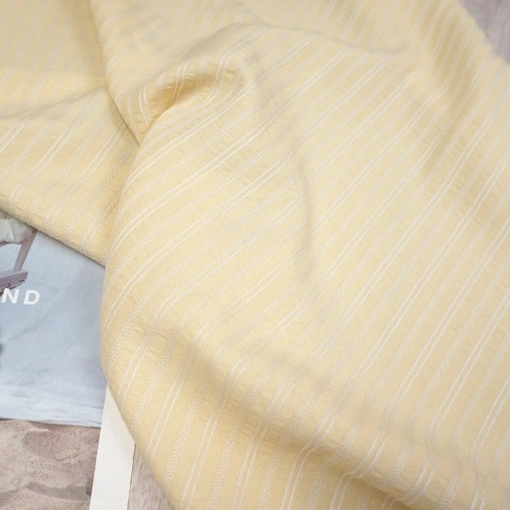 Longan Craft’s Striped Rayon Dobby Fabric by the Yard features soft, light yellow polyester jacquard dobby material with thin white stripes—perfect for blouses. Its subtle textured weave adds airy elegance to any sewing project.
