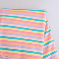 A folded Longan Craft Striped Jersey Fabric By The Yard, a stretchable cotton spandex textile with horizontal pastel yellow, green, pink, and purple stripes, is laid on a light gray surface—perfect for DIY short sleeves.