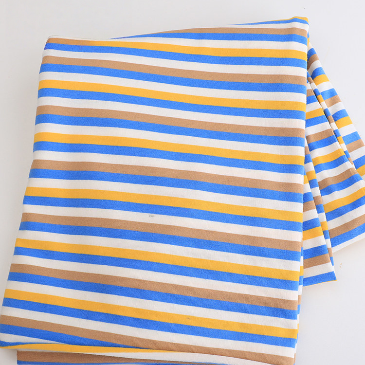 A piece of Longan Craft's Striped Jersey Fabric By The Yard, a stretchable cotton spandex jersey in blue, yellow, white, and light brown horizontal stripes for DIY short sleeves, rests folded on a white surface.