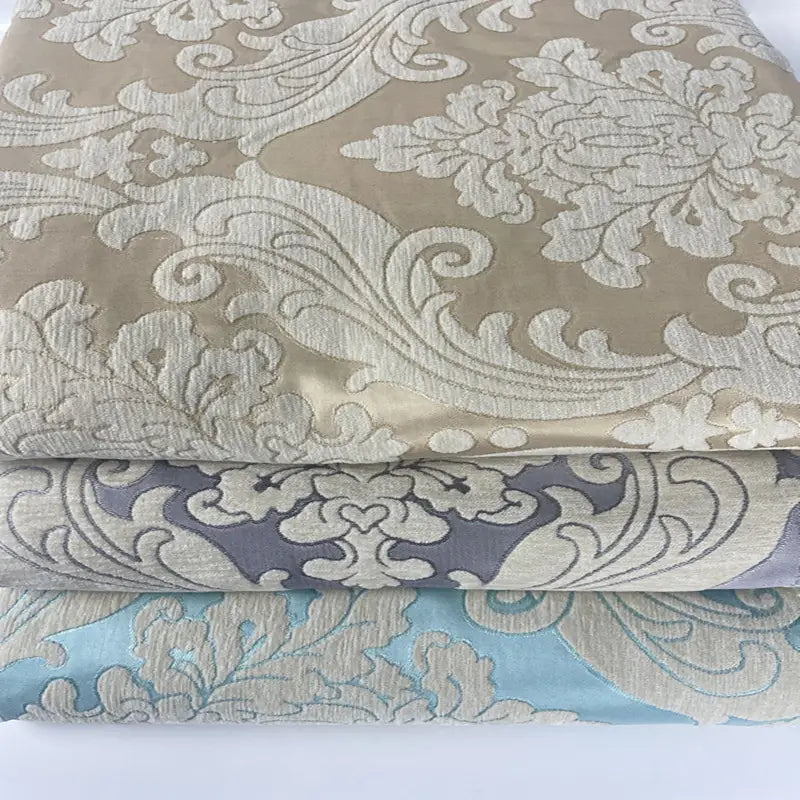 Three folded fabrics in beige, gray, and light blue with embossed floral and leaf designs—ideal as Thick Chenille Damask Fabric By The Yard by Longan Craft for vintage jacquard upholstery or elegant home décor projects.