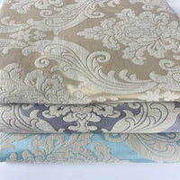 Three folded fabrics in beige, gray, and light blue with embossed floral and leaf designs—ideal as Thick Chenille Damask Fabric By The Yard by Longan Craft for vintage jacquard upholstery or elegant home décor projects.
