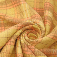 A close-up of Thick Plaid Mammoth Flannel Fabric by the Yard from Longan Craft, swirled in a spiral to display its yellow and orange intersecting lines and soft, heavyweight cotton brushed texture—ideal for anyone seeking warm flannel apparel fabric.