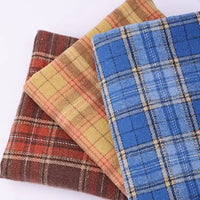 Three folded pieces of Thick Plaid Mammoth Flannel Fabric By The Yard from Longan Craft—in shades of brown, yellow, and blue—are arranged atop a light background, showcasing this heavyweight cotton brushed flannel material that’s perfect for cozy apparel projects.