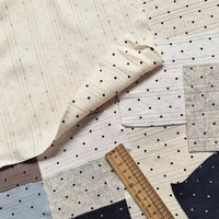 Samples of Tiny Polka Dot Print Pointelle Fabric By The Yard in various colors featuring a ribbed texture and tiny polka dot patterns, shown with a wooden ruler for scale.