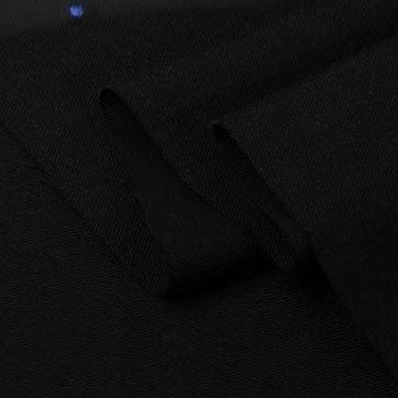 A close-up of Longan Craft Twill Cotton Lyocell Fabric by the yard in solid black, showing a visible fold that highlights its smooth texture and soft, comfy, breathable material—ideal for shirts.